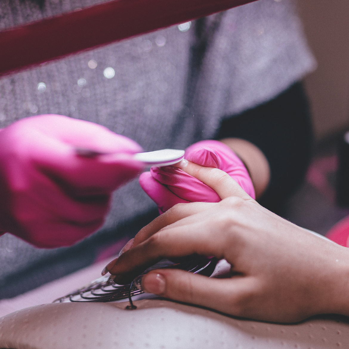 A woman receiving a manicure while wearing pink gloves, showcasing a serene and pampering beauty treatment experience.